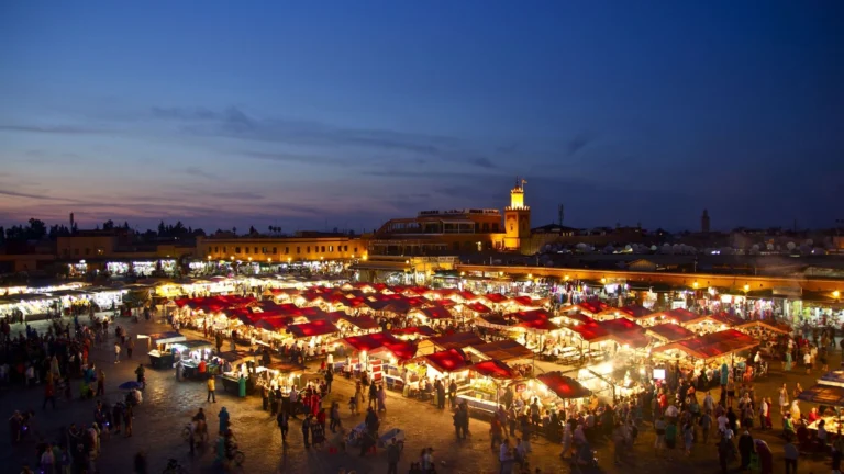 Plaza Jemaa el-Fna en Marrakech con puestos de comida y músicos tradicionales al atardecer