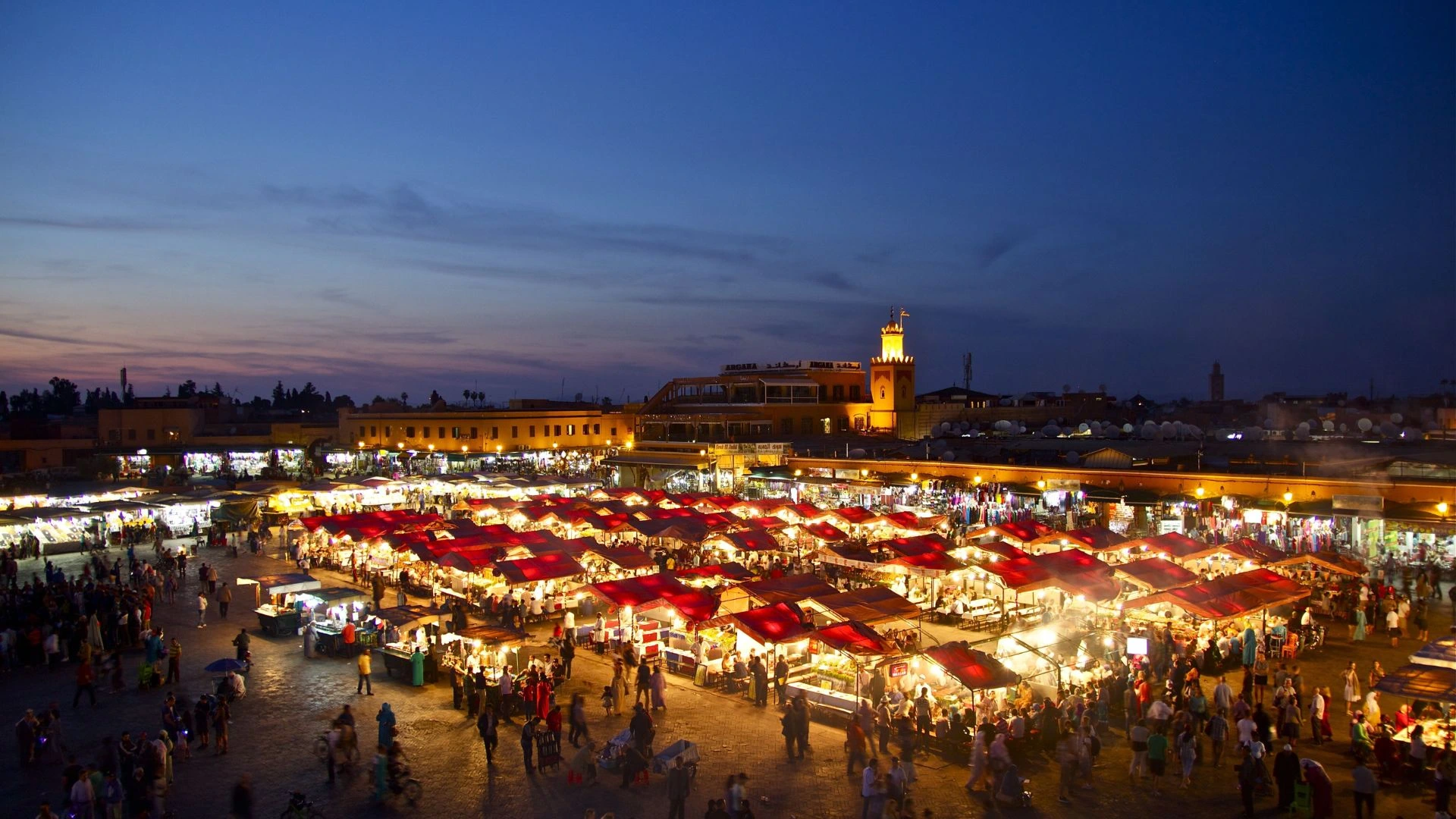 Plaza Jemaa el-Fna en Marrakech con puestos de comida y músicos tradicionales al atardecer