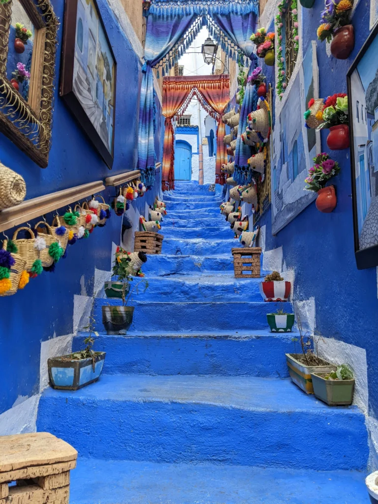 Calle empedrada de Chaouen con casas pintadas de azul y flores