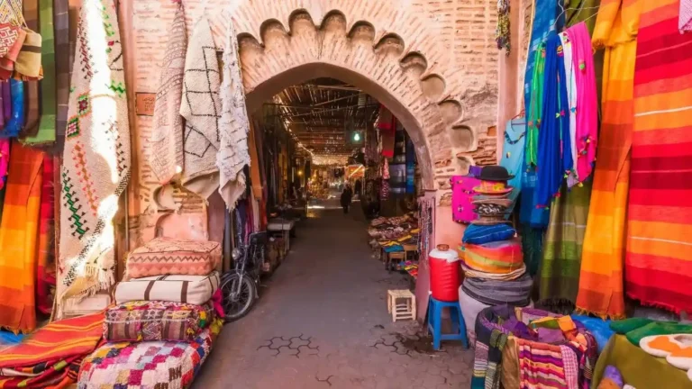 Vendedor de especias en un zoco tradicional de Marrakech, con sacos de colores vivos y ambiente animado.