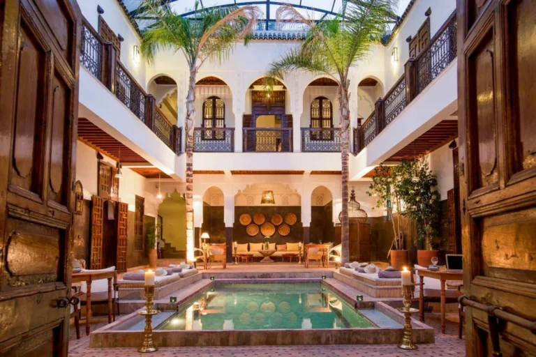 Patio tradicional de un riad de lujo en Marrakech con fuente central y decoración marroquí.